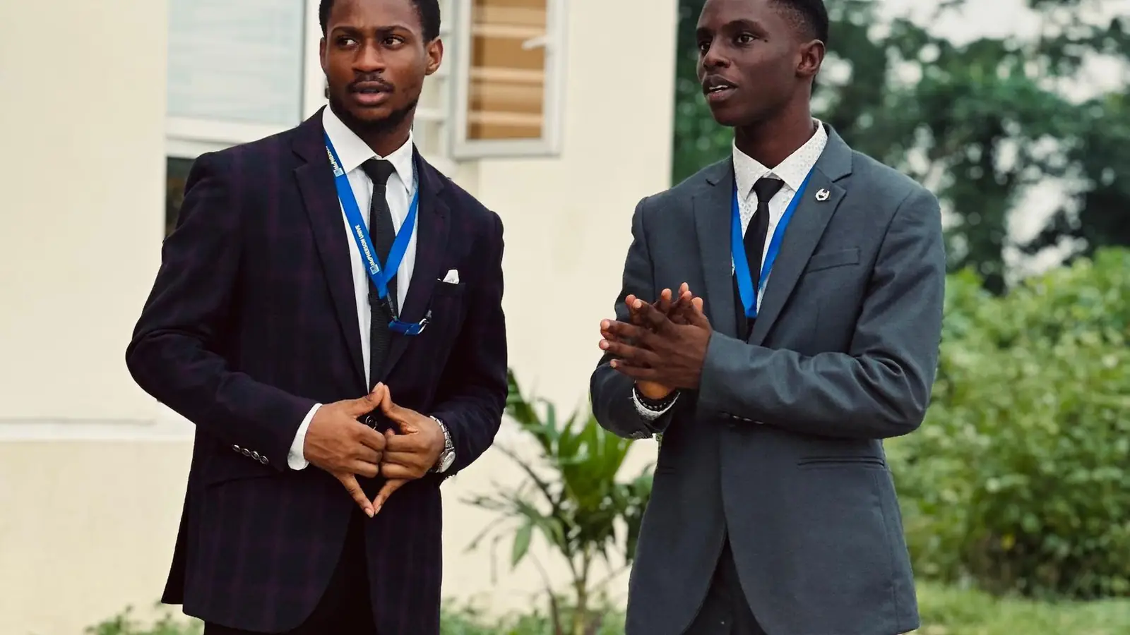 Two young men in suits talking outside a conference venue