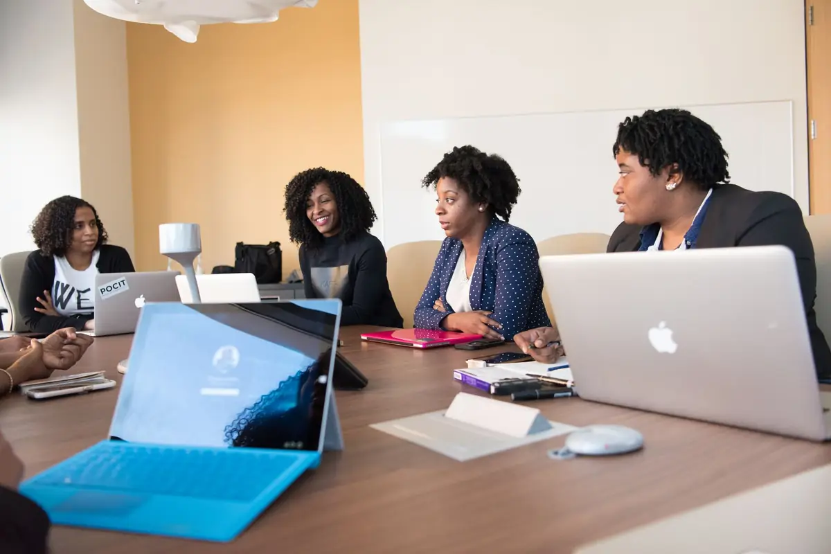 Four professional women in a meeting around a table with laptops