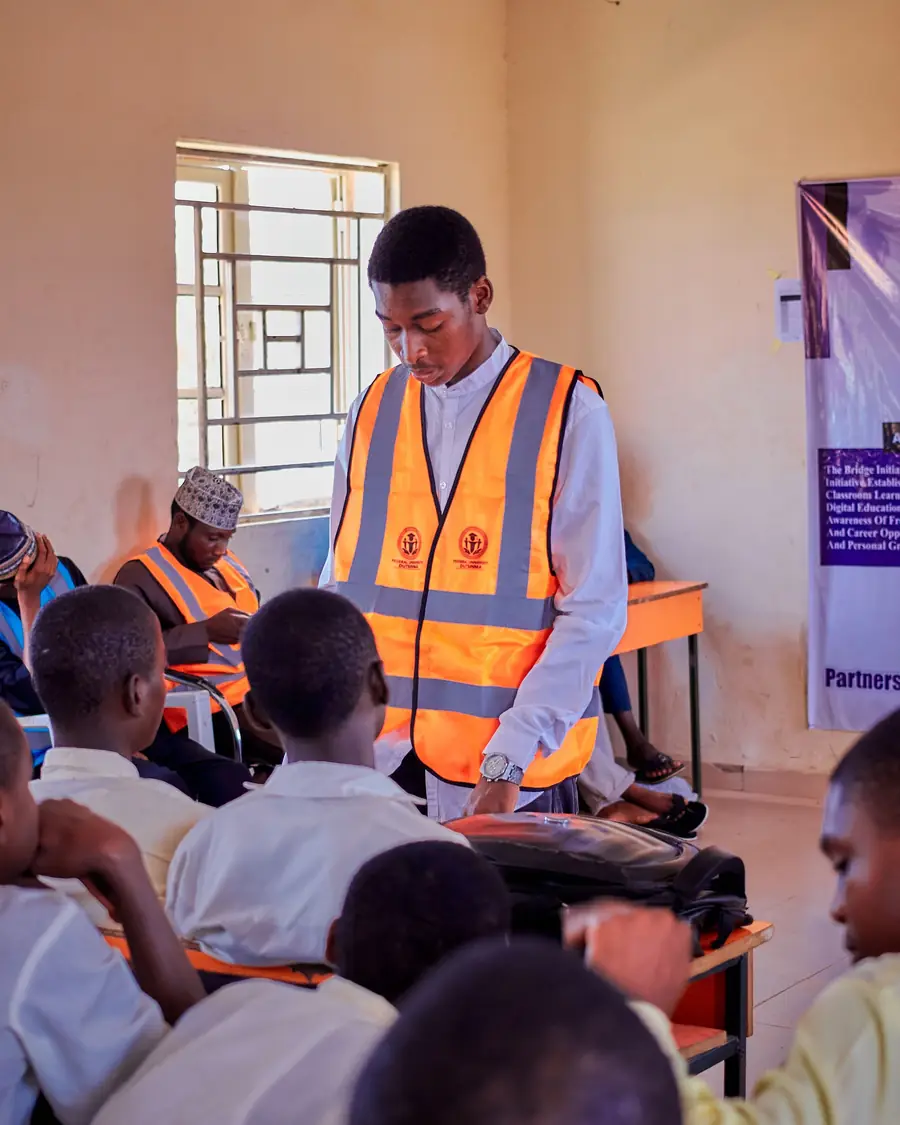 A facilitator in a high-visibility vest leading a session with a class of secondary-school students