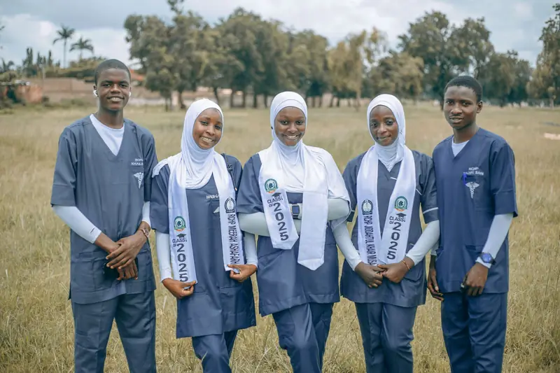 Five university nursing students in scrubs standing together on campus