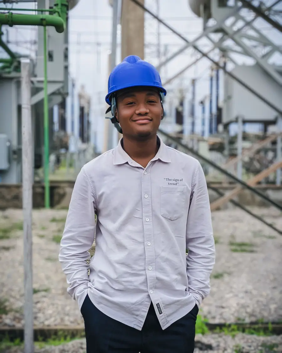 A young engineer in a hard hat standing at an electrical substation